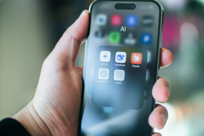 A hand holds a smartphone with various apps